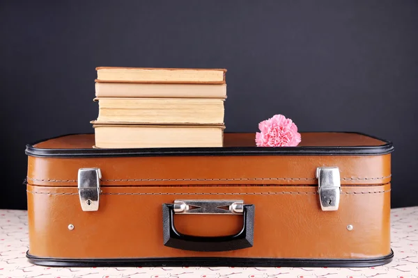 Valise vintage avec pile sur livres sur surface à motifs et fond sombre — Photo