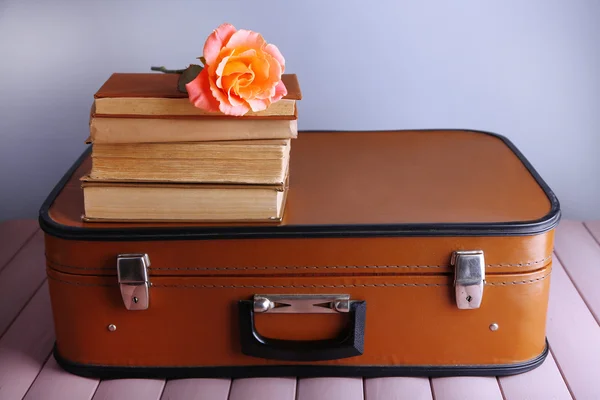 Vintage-Koffer mit Bücherstapel auf gemusterter Oberfläche und hellem Hintergrund — Stockfoto