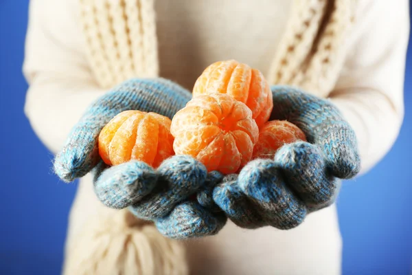 Verse rijpe mandarijnen in vrouwelijke handen, close-up, op blauwe achtergrond — Stockfoto