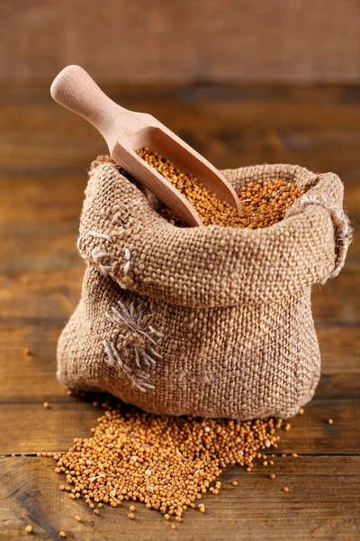 Mustard seeds in bag on  wooden background — Stock Photo, Image