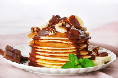 Nane, ceviz, çikolata ve ahşap plakalar arka plan üzerinde kumaş ile masada muz dilimleri ile krep yığını