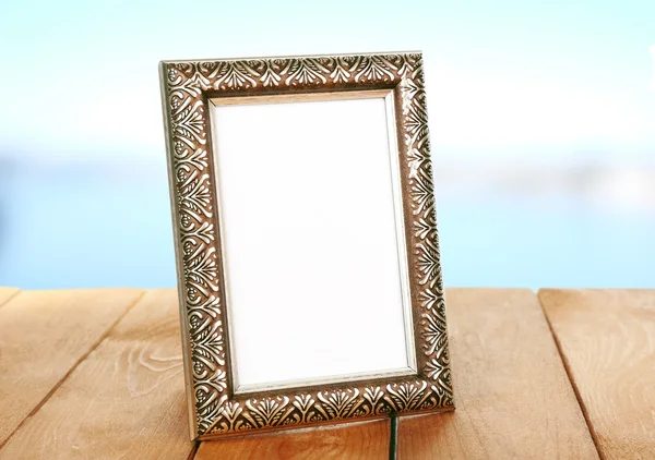Photo frame on wooden table on blue background — Stock Photo, Image