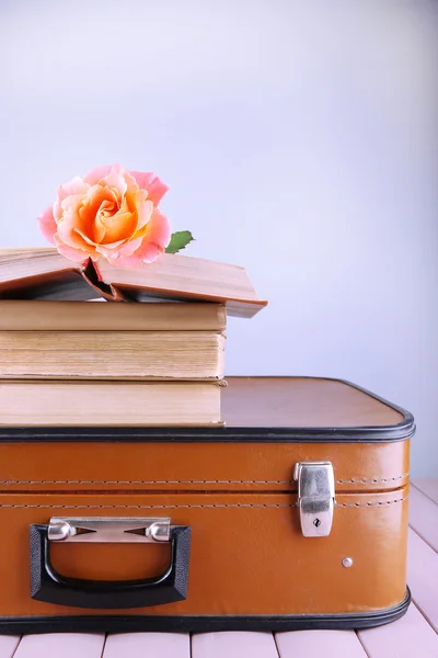 Vintage-Koffer mit Bücherstapel auf gemusterter Oberfläche und hellem Hintergrund — Stockfoto