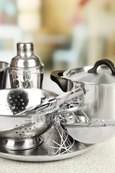 Stainless steel kitchenware on table, on light background — Stock Photo, Image