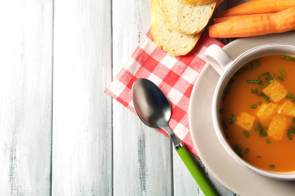 Sup wortel, krim dan sendok, pada warna latar belakang kayu — Stok Foto