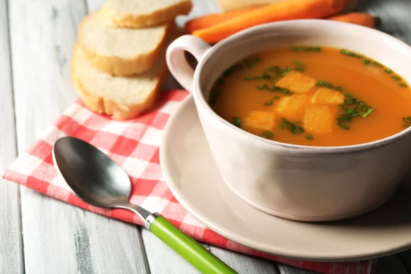 Sup wortel, krim dan sendok, pada warna latar belakang kayu — Stok Foto