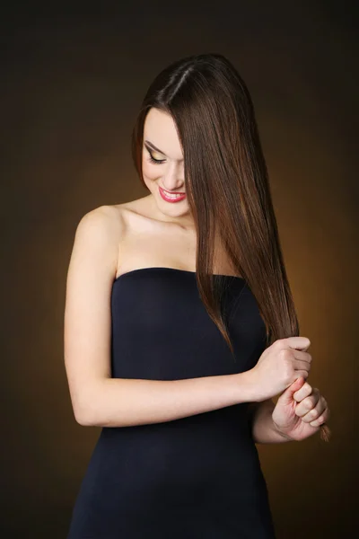 Belle jeune femme aux cheveux longs sur fond brun foncé — Photo