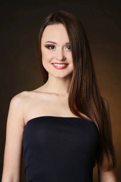 Beautiful young woman with long hair on dark brown background — Stock Photo, Image