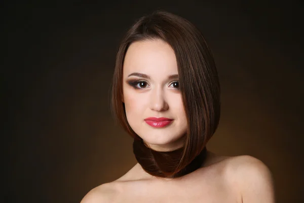 Beautiful young woman with long hair on dark brown background — Stock Photo, Image