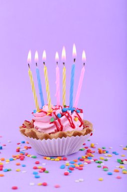 Doğum günü kek mumlar ve mor arka plan üzerinde renkli parıldıyor
