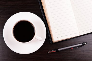 Fincan kahve tabağı ile günlüğü üzerinde ve ahşap masa arka plan üzerinde kalem