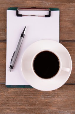 Fincan kahve fincan tabağı üzerinde kağıt ve kalem ahşap masa arka plan üzerinde levha ile