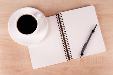 Fincan kahve üzerinde uçan daire ile defter ve kalem ahşap masa arka plan üzerinde