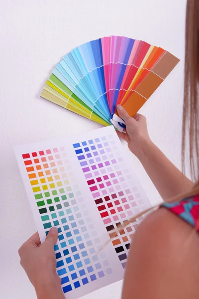 Kvinna väljer färg för vägg från kompresser i rummet — Stockfoto