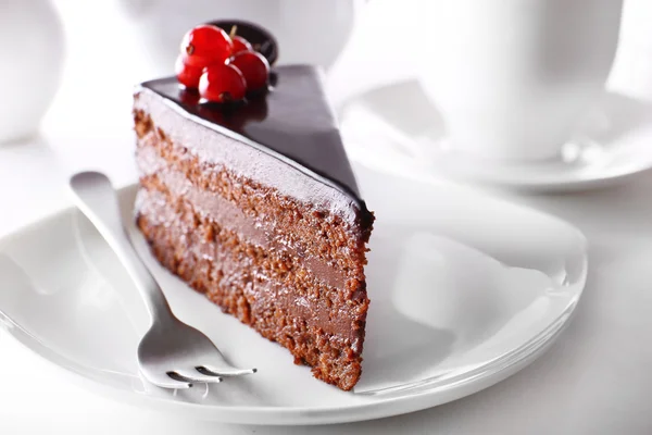 Delicioso pastel de chocolate en el plato en la mesa sobre fondo claro — Foto de Stock