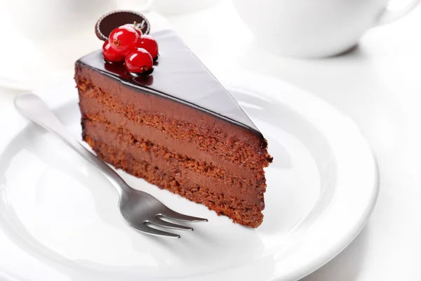 Delicioso bolo de chocolate na placa na mesa no fundo claro — Fotografia de Stock