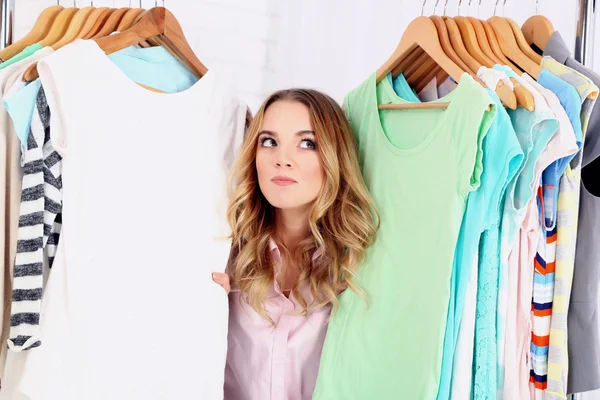 Mooie jonge vrouw in de buurt van rack met hangers — Stockfoto