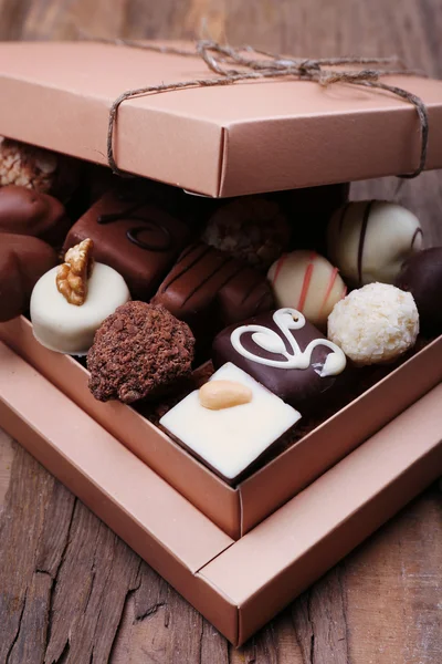 木製の素朴な背景の上にチョコレートでいっぱいのボックス — ストック写真
