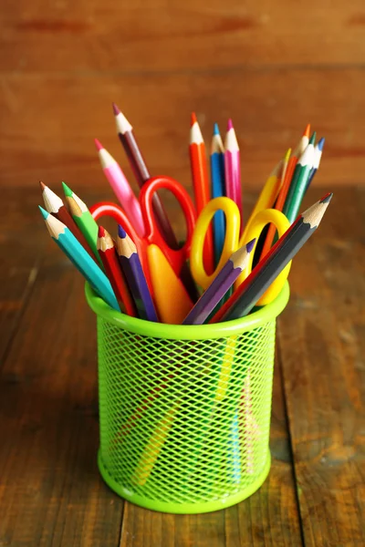 Красочные карандаши с ножницами в металлическом держателе на деревенском деревянном фоне — стоковое фото