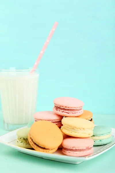 Assortimento di delicati macaron colorati e vetro con latte su sfondo di legno a colori — Foto Stock