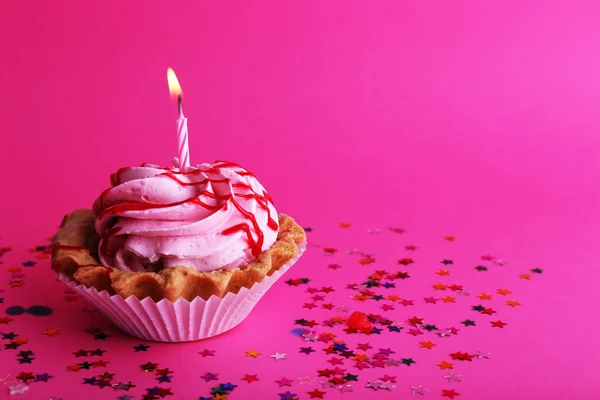 Narozeninový dort cup s svíčku a barevné hvězdy na růžovém pozadí — Stock fotografie