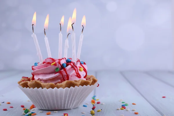 Narozenin cup dort se svíčkami a jiskří na dřevěný stůl barvy a světlé pozadí — Stock fotografie