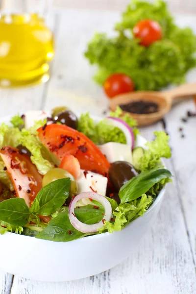 Greek salad in plate on color wooden table background — Stock Photo, Image