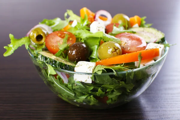 Salade grecque dans un plat en verre sur fond de table en bois — Photo