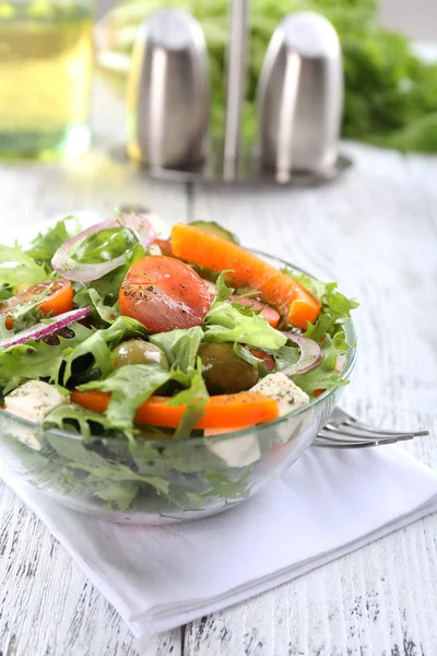 Salada grega em prato de vidro em guardanapo e cor de fundo de madeira — Fotografia de Stock