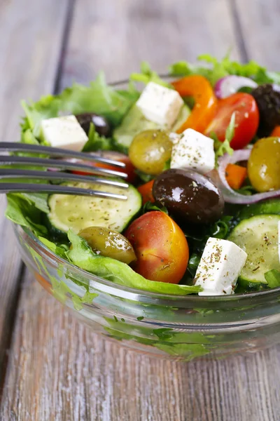 Griekse salade in glas schotel met vork op houten achtergrond — Stockfoto