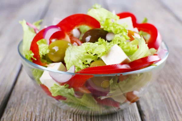 Greek salad in glass dish on wooden table background — Stock Photo, Image