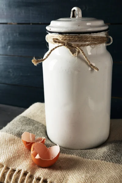 Milchkanne mit Eierschale auf farbigem Holzhintergrund — Stockfoto