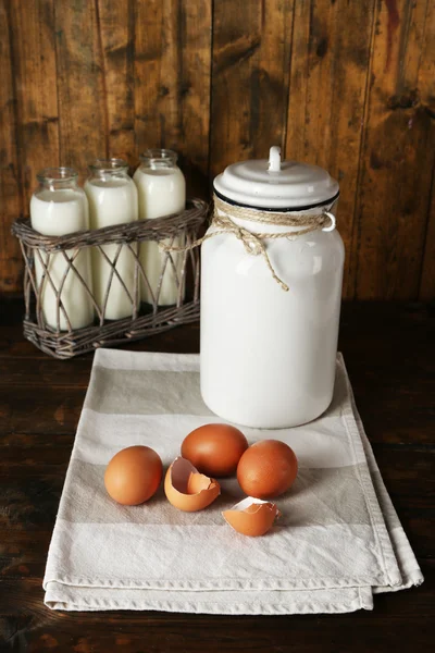 Milk can with eggs, eggshell and  glass bottles on rustic wooden background — Stock Photo, Image