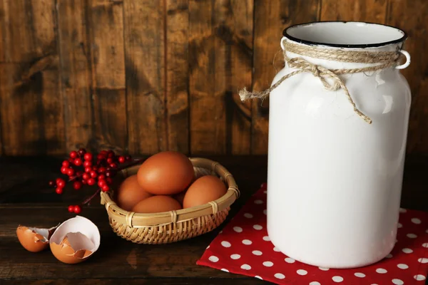 Milk can with eggs and eggshell on rustic wooden background — Stock Photo, Image