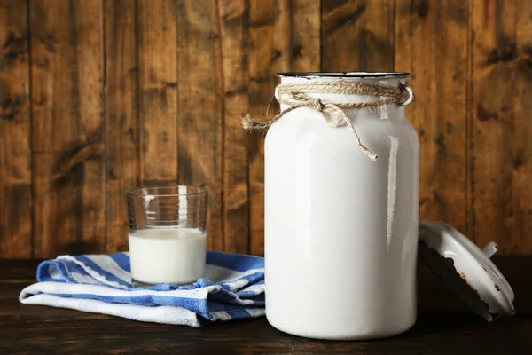 Offene Milchkanne auf Spültuch auf rustikalem Holzgrund — Stockfoto