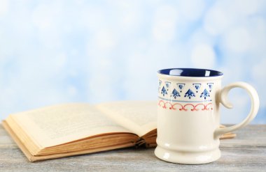 Fincan çay ve masaya parlak arka plan üzerinde kitap