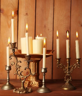 Retro candlesticks with candles on wooden background clipart