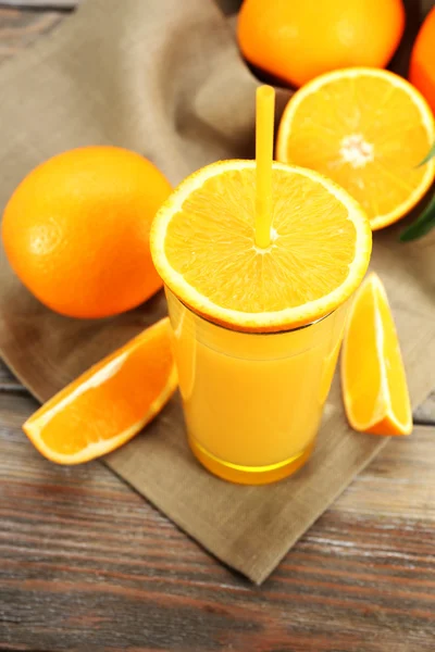 Glas Orangensaft mit Stroh und Scheiben auf Holztischhintergrund — Stockfoto