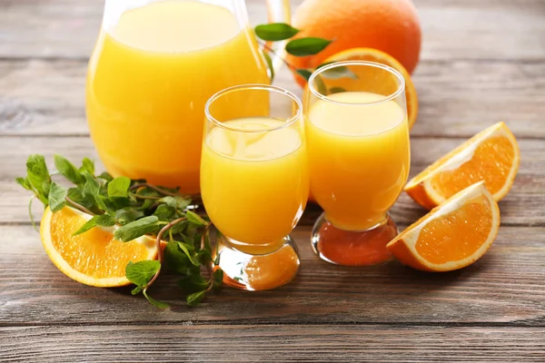 Kieliszek soku pomarańczowego i plastry na drewnianym stole tło — Zdjęcie stockowe