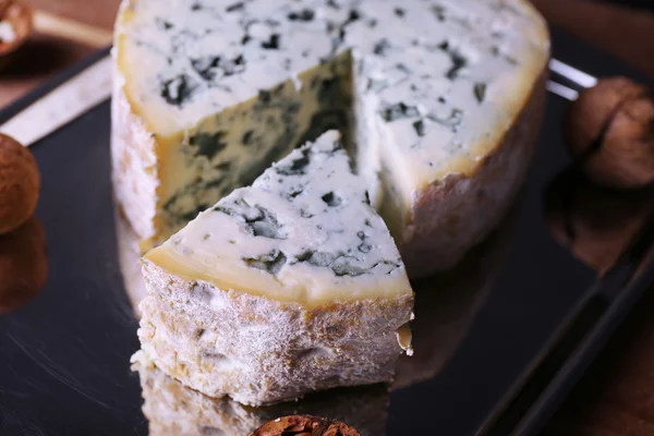 Blue cheese with nuts on metal tray and wooden table background — Stock Photo, Image