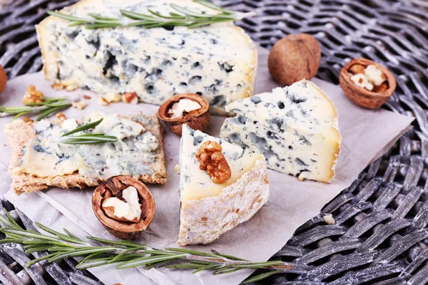 Blue cheese with sprigs of rosemary and nuts on wicker mat background — Stock Photo, Image