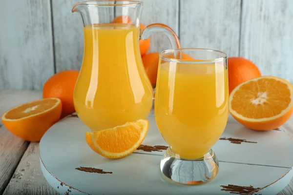 Склянка апельсинового соку зі скибочками на кольоровому дерев'яному фоні — стокове фото