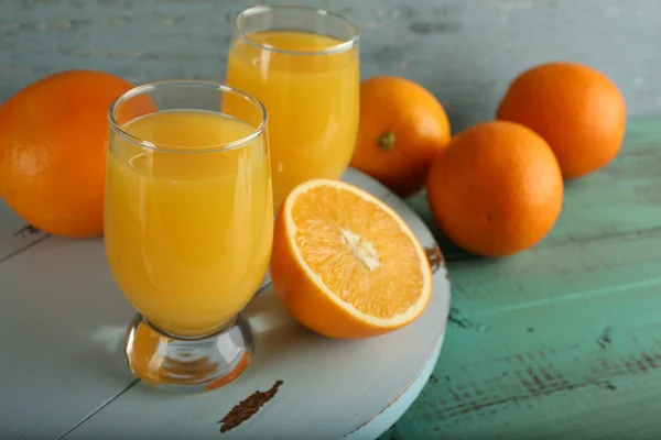 Склянка апельсинового соку зі скибочками на кольоровому дерев'яному фоні — стокове фото