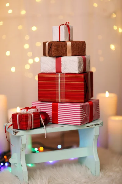 Pile of Christmas present boxes on wooden stool, on bright background — Stock Photo, Image