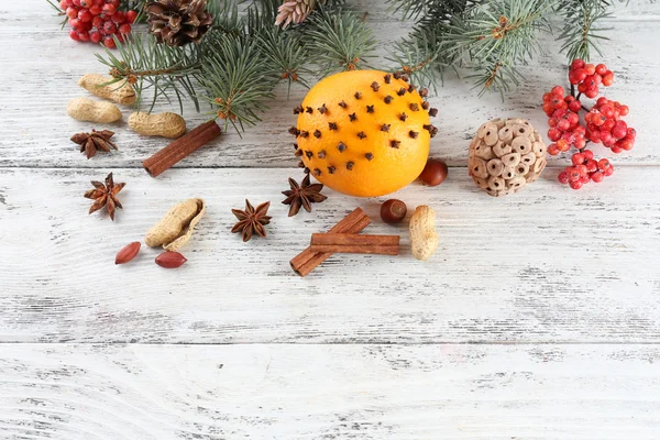 Orange with spices, rowan, and Christmas pine sprig on color wooden background — Stock Photo, Image