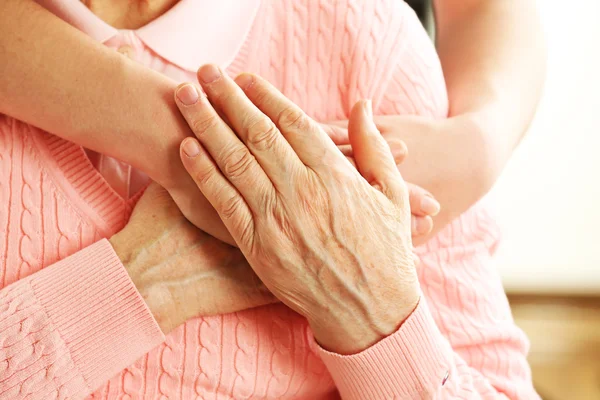 Old and young hands hug, closeup