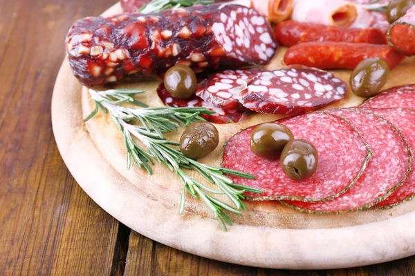 Assortment of sausages on cutting board and wooden table background — Stock Photo, Image