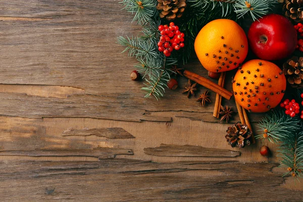 Früchte mit Nüssen, Gewürzen und Tannenzweigen auf rustikalem Holzgrund — Stockfoto
