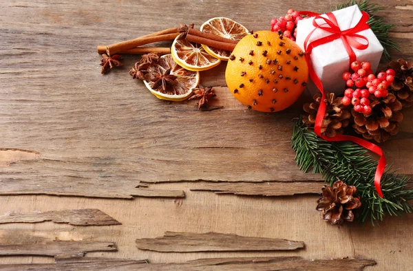 Oranje met huidige doos, specerijen, segmenten van uitgedroogde citroen en takjes kerstboom op rustieke houten achtergrond — Stockfoto