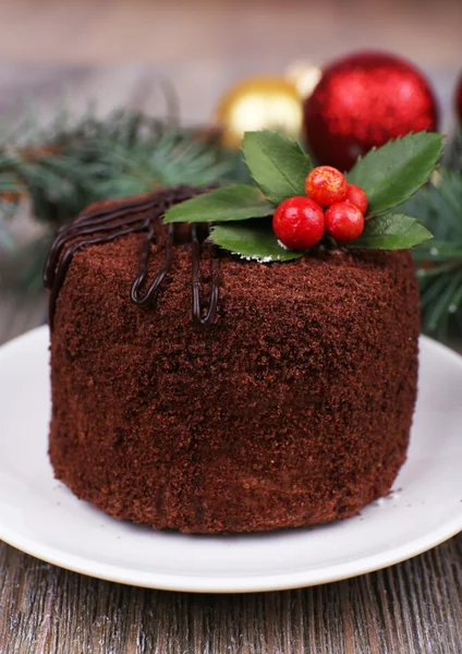 Läcker chokladkaka på tefat med holly och bär på Juldekoration och trä bakgrund — Stockfoto